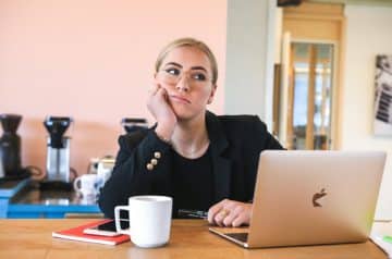 Overcoming procrastination strategy, woman in black long sleeve shirt using macbook